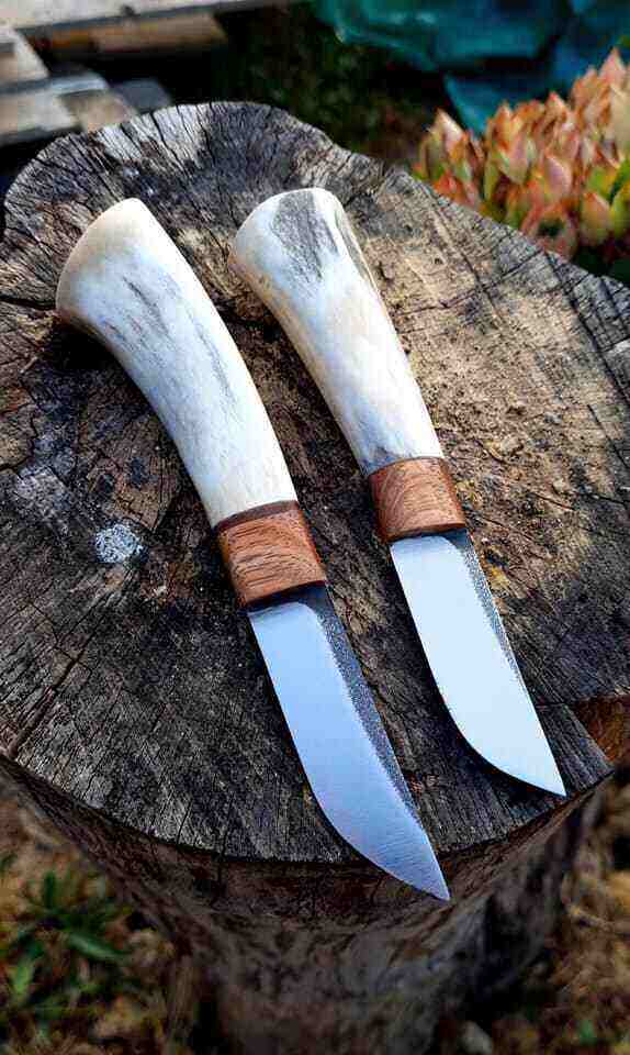 Dva noža sa belom drškom na panju