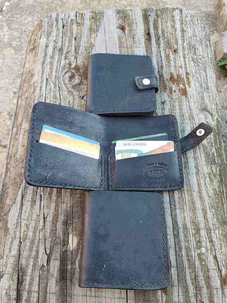 Tri kožna novčanika na drvenom stolu