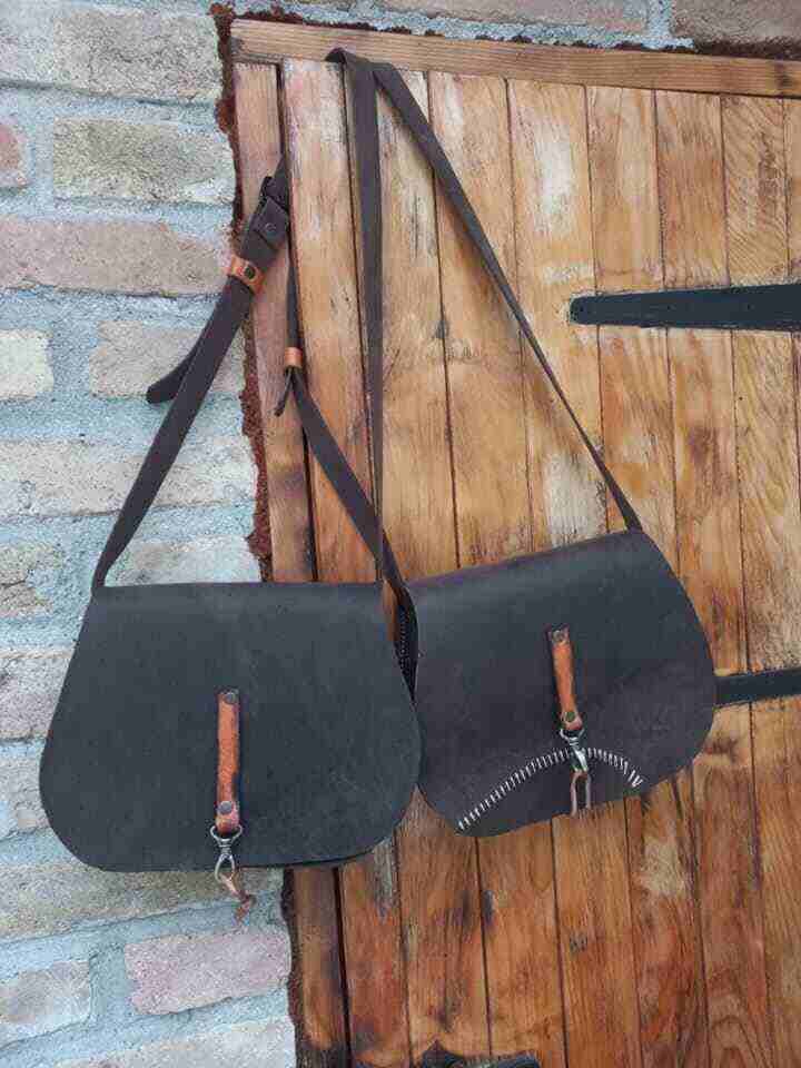 Dve kožne torbe vise na drvenim vratima