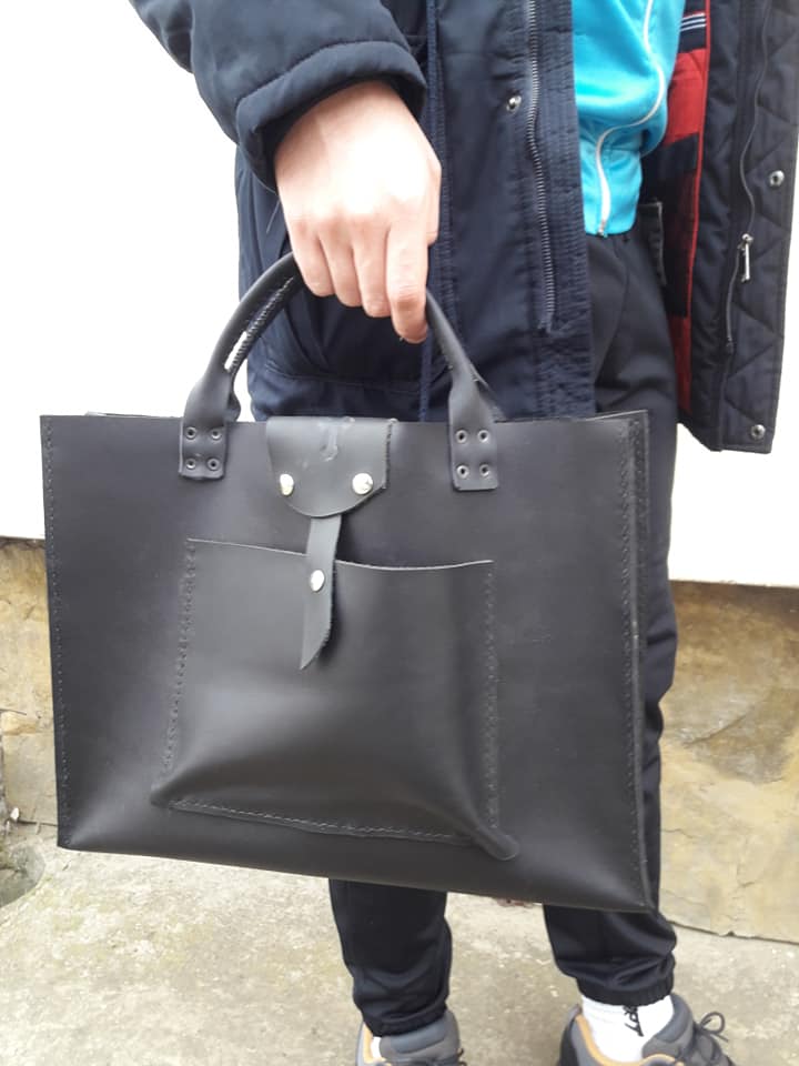 Čovek nosi crnu kožnu tašnu